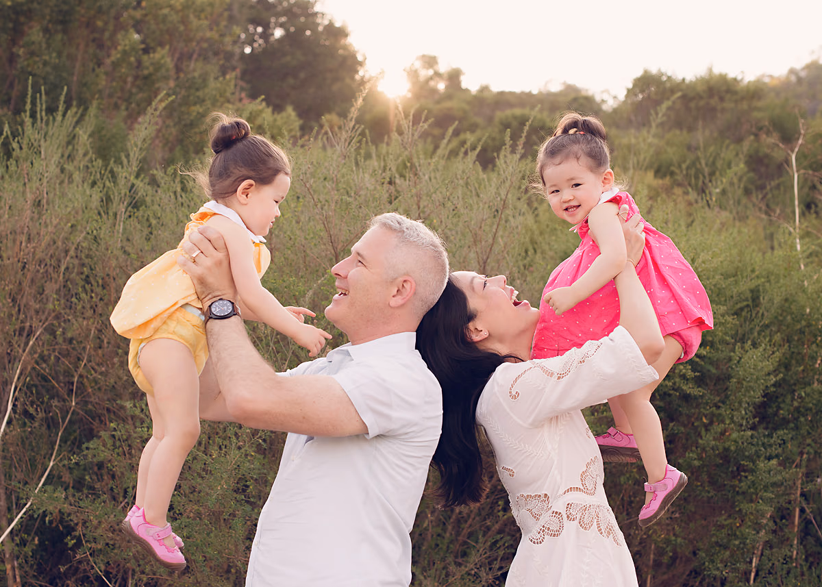 Parents lifting their two laughing children in the air at sunset by Alicia Cervenka Photography